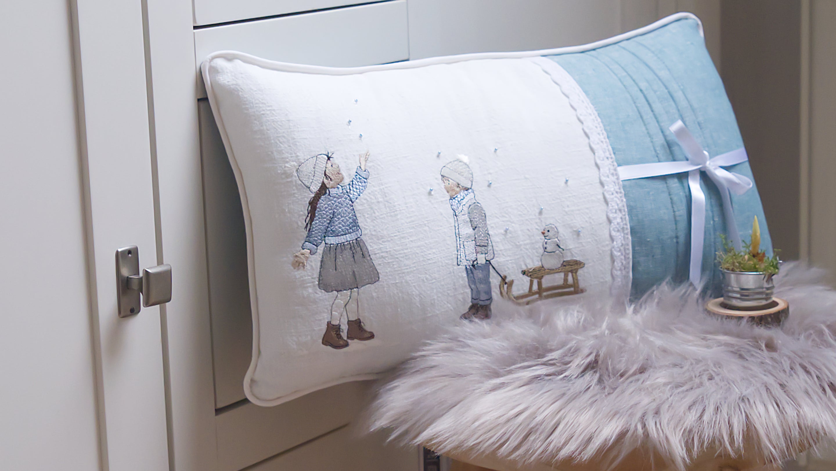 Stickdateien Schneekinder Junge und Mädchen im Schnee mit Schlitten und Schneemann. Besticktes Kissen mit Biesenverarbeitung. Hergestellt in Deutschland