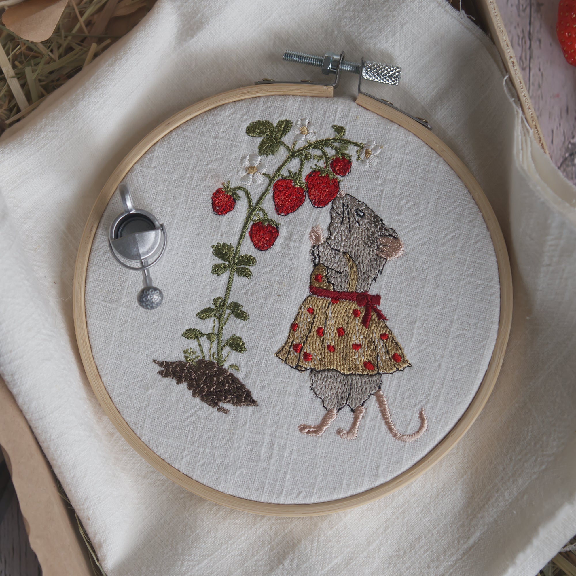 Stickdatei Maus schnuppert an einer Erdbeerpflanze mit roten Erdbeeren. Sommerliches Gartenmotiv aus der Erdbeermäuse Serie im Stickrahmen.
