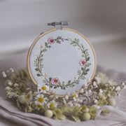 Stickdatei Wiesenkranz 10x10 mit Margeriten, rosa Wildblumen und Kräutern als runder floraler Rahmen auf Leinen, ideal für Kissen, Patchwork und personalisierte Stickprojekte im Landhausstil