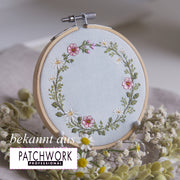 Stickdatei Wiesenkranz 10x10 mit Margeriten, rosa Wildblumen und Kräutern als runder floraler Rahmen auf Leinen, ideal für Kissen, Patchwork und personalisierte Stickprojekte im Landhausstil bekannt aus Patchwork Professional