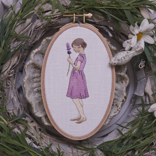 Stickdatei Mädchen mit Lavendelzweig im Kleid im Stickrahmen auf hellem Stoff